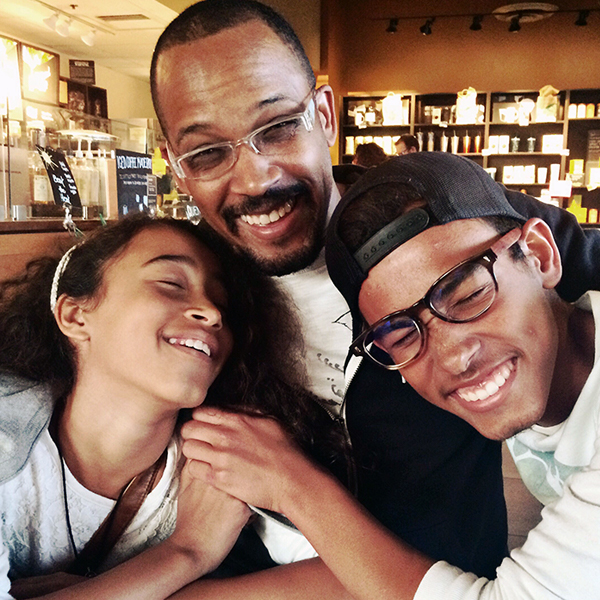 Photo of father, daughter and son hugging and laughing