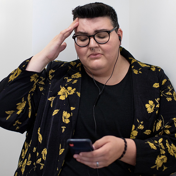 Photo of transgender person looking at phone with stressed expression