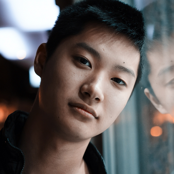 Photo of young asian man leaning against window
